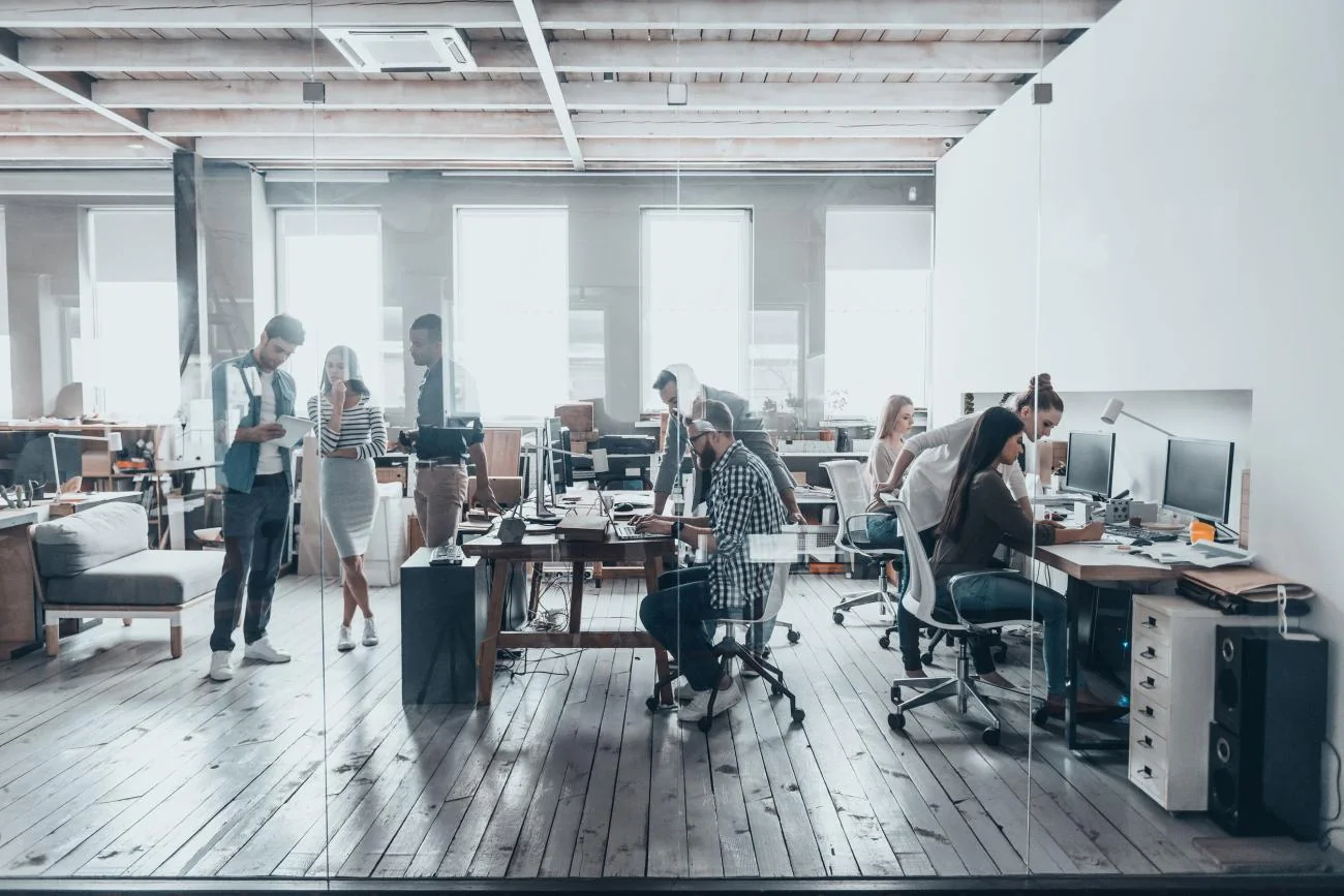 Colleagues collaborating around desks in a modern office workspace